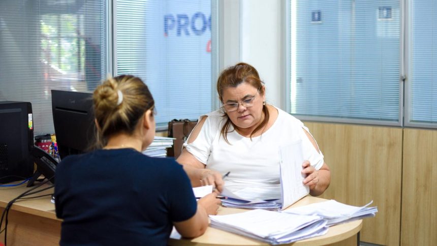 Duas mulheres em escritório oo Procon-AM analisando documentos. Uma delas usa óculos e veste branco.