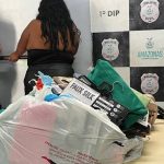 Duas mulheres em uma sala com evidências apreendidas, incluindo roupas e sacolas plásticas.